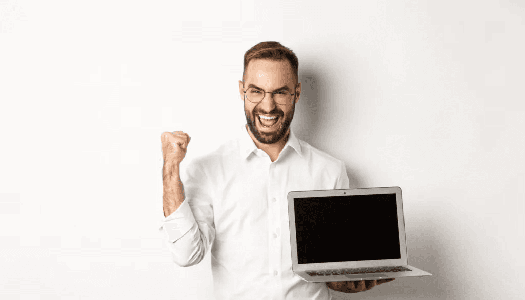 Homem comemorando com notebook em mãos